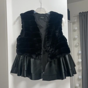 Väst - skinn - Skinn väst. Som ni ser på bilden har den 2 olika material på övredelen och underdelen. Den är helt ny, använd bara 1 gång. 