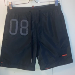 Superdry badbyxor - Snygga shorts/badbyxor från superdry i strl xs med 3 fickor, en med dragkedja. Väldigt sparsamt använda, säljes pga fel storlek 