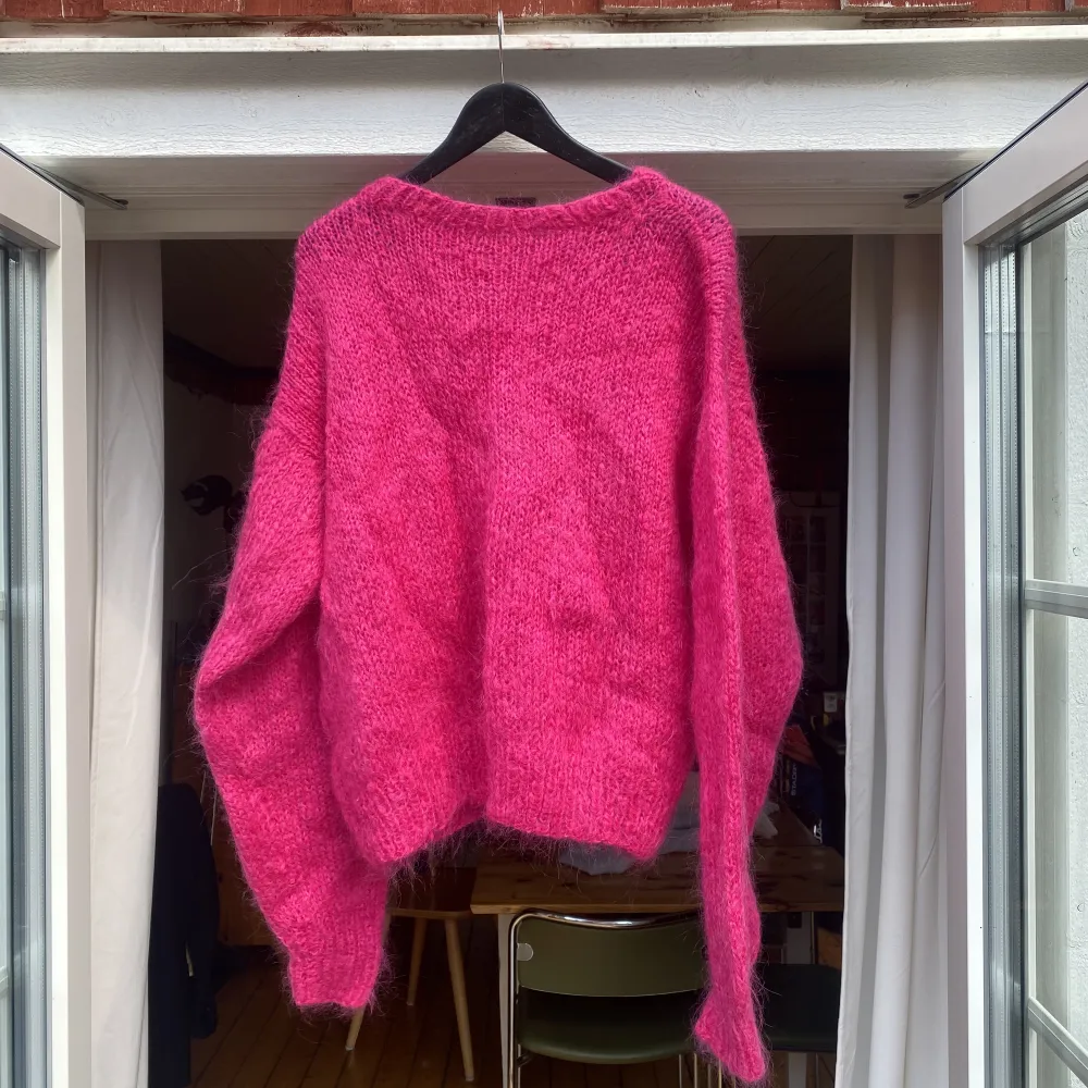 En tjock stickad tröja i vad jag tror är en Ull blandning eller liknande. Jättefin djup och intensiv rosa. Den är hemmastickad och skulle uppskatta den som en S-M. Fint skick. Lite små-skrynklig endast då den legat i garderoben ☺️. Stickat.
