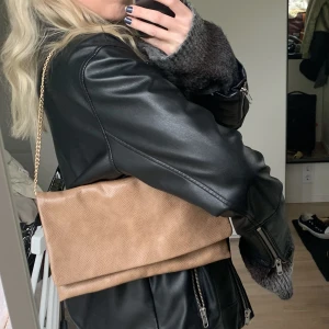 Brun/beige handväska - Brun/beige handväska i ormskinsmönster från Hallhuber. Väldigt fin kvalitet! Nypris omkring 600-700kr. Guldkedja som band. Går att ha som axelväska samt axelremsväska som på bilderna. Som ny i skicket! Finns fler bilder 😊