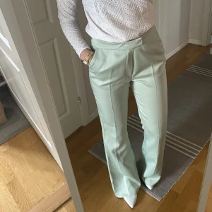 Mintgröna kostymbyxor  - Mintgröna kostymbyxor från Gina Tricot, storlek 38! Jag har sytt dit en extra knapp och gjort ett extra hål då de var lite stora i midjan för mig som har 36. Inget som syns utifrån eller stör användningen av originalknäppningen! 150 kr + frakt 🥰