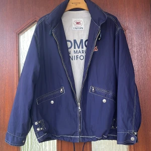 Vintage jacka storlek M-L - Praktisk inrullad tunn huva finns på jackan Dragsko nedtill  Är osäker på märket men på märket står det UNIFORM! 