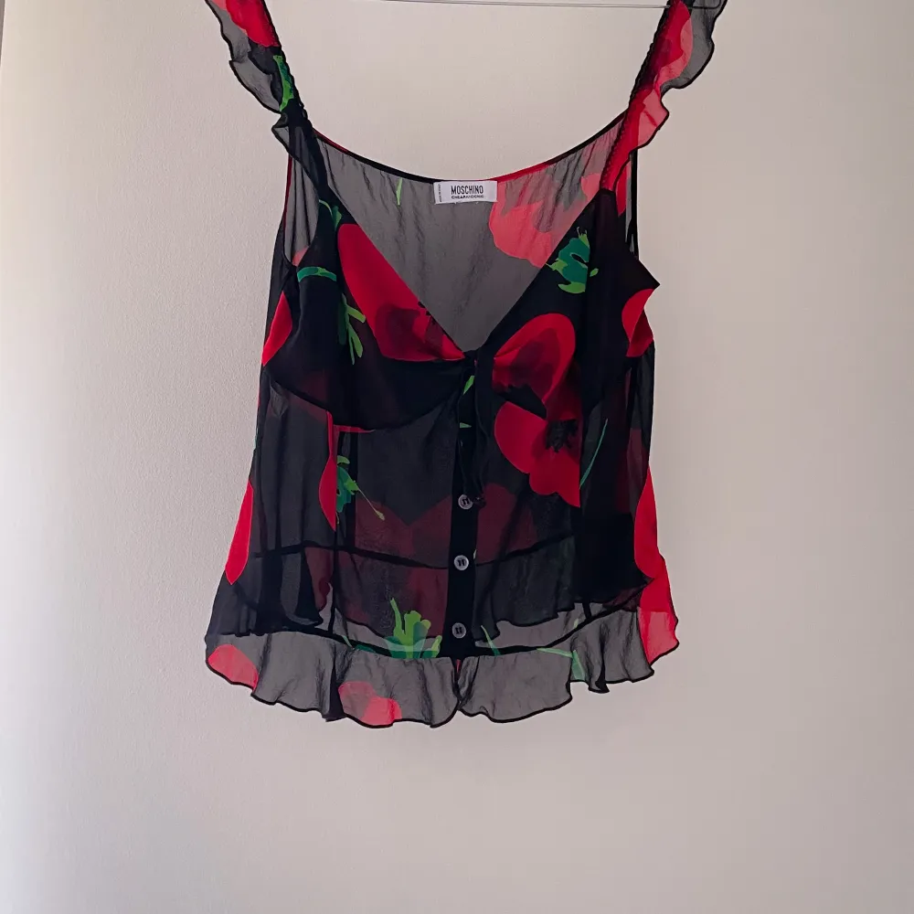 Rose Print & Black Pearlized Buttons. Flirty Details with Frontal Tie Feature as well as Ruffle Straps and Skirted Hem. Very Good Condition. Made in Italy.   50 CM/ 19.7 IN Length 80 CM/ 31.5 IN Chest 80 CM/ 31.5 IN Waist  . Blusar.