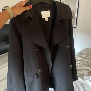 Trenchcoat hm - Jättefin trenchcoat från hm i Strl Xs. Endast använd en gång så den är i toppen skick. Tunn så passar bra som sommar/höst jacka. Nypris 699kr