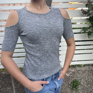 Cold shoulder topp, gråmelerad  - Cold shoulder topp, gråmelerad. Fler bilder finns att få. Mått armhåla till armhåla: 39cm. Längd: 56cm. Supersöt! Mycket fint skick. Lapp inuti bortklippt. Jättefin till jeans!