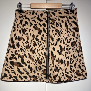 Minikjol - Minikjol köpt i USA med dragkedja som går att öppna hela vägen. Kjolen är ca 40cm lång ca 36cm bred i midjan.