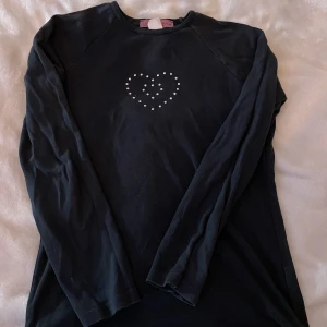 Svart långtröja med hjärta - En söt svart långtröja med ett gulligt hjärta på av silver ”pluppar” från ”unlookenx” köpte på second hand. säljer pga att den inte är i min stil längre men den är i bra skick. Köparen står för frakt och pris kan diskuteras💕