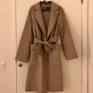 Kappa - En super härlig varm kappa från zara. Den är i en Såå fin beige färg som framgår i andra bilden där det är dagsljus. Den är i ett finare material så den får inte massa nopper osv. 