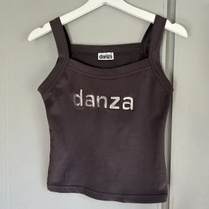 Vintage grå Danza topp! - Säljer denna vintage Danza linne på grund av att den inte passar mig! Tröjan är i väldigt fint material och har märkets namn ”Danza” på framsidan i silver färgade bokstäver! Storlek M! Använd köp nu funktionen❤️
