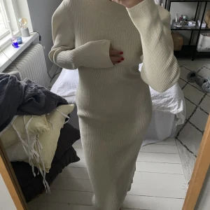 Stickad klänning  - Jättefin stickad klänning i ribbat material. Inte använd många gånger.slutar nedanför knäna på mig som är 175 cm lång! Vit-beige färg. Storlek M, men passar även S.  