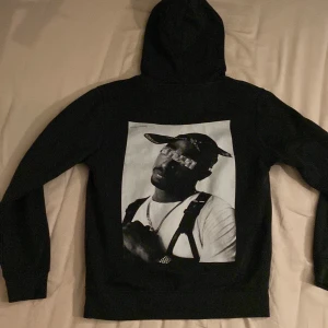 Tupac hoodie - Jag säljer den här feta tupac hoodien från icons living i st xs då den blivit för liten. Skick 7/10 inga fläckar eller hål men luvan är lite platt