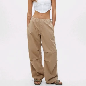 Beige baggy parachute pants - Helt nya oanvända parachute pants från Pull and Bear som är för små på mig som har 42 i byxor. Står L men passar baggy S-M. Helt ny med tags, köpt för typ 300kr Möts upp I Stockholm