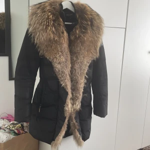 Hollies jacka  - Jackan är i väldigt fint skick använd under bara 1 säsong då jag gått ner i vikt mycket. Slitage bara på pälsen fram där man knäpper i övrigt mycket fin skick. Har ej kemtvättat men kommer från ett djur och rökfritt hem. Denna modellen säljs inte längre. 