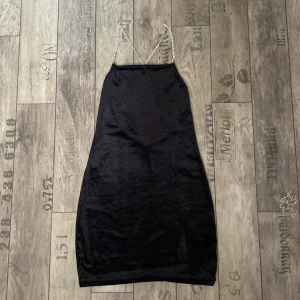 Tajt svart klänning  - Tajt svart klänning med kristall band som går i kors på ryggen. Oanvänd