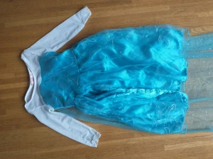 Frost Elsa klänning + stav (100cl) - Elsa klänning med trollspö Storlek 100cl (2-3 år) Sömnad har släppt längst ner på klänningen. Se sista bilden.  Finns att hämta i Västra Frölunda. Snabb hämtning priorernas.