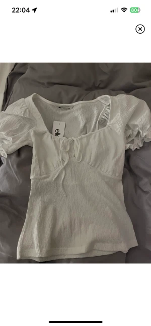 Blus - Jättefin helt ny topp, perfekt till sommaren! Aldrig använd, endast testad, lappen kvar och allt. Puffärmar och utsvängd nertill. Från Ellos, strl 34/36 (minsta storleken). Säljer för 200kr.