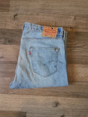 Blåa Levis 501 jeans! - Säljer mina gamla levis jeans då de är för små för mig. Passformen är mer åt straight fit. Obs: lagat hål på vänster ben. 