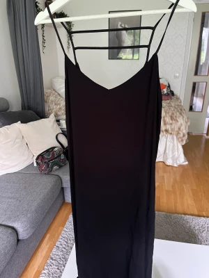 Klänning  - Svart klänning, rak modell med slits på båda sidorna, sparsamt använd och i väldigt fint skick