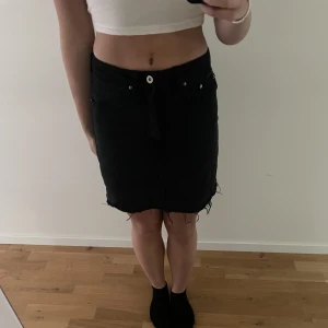 Svart jeanskjol - Svart jeanskjol. Fick den för några år sen och lyckas inte läsa mig till var den är ifrån. Har bytt ut dragkedjan då den gamla sprack. Kan bäras både som högmidjad och lågmidjad.