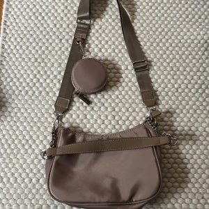 Väska - En beige väska med snygga detaljer, går att justera axelbandet, frakt tillkommer 