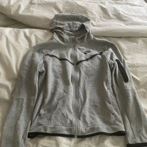 Nike tech fleece  - En grå nike tech fleece i bra skick, storlek 158-170 men skulle säga att den passar upp till ungefär 173. Inga skador förutom en liten fläck längst ute på ärmen som man ser i bild 3. 
