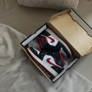 AIR JORDAN 1 MID White/Gym Red-Black - Säljer mina Jordans då jag inte använder dom. Köpta från Dubbleboxed (UK), använda max 5 gånger. Lådan har jag men inte kvittot tyvärr. Lite creasade men annars i bra skick, nypris 3000.