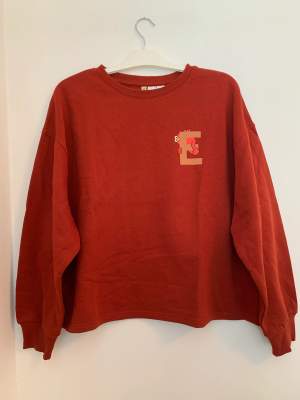 Ny, oanvänd, croppad, Elmo sweatshirt från H&M Divided i storlek L.  Sweatshirten är tegelröd.