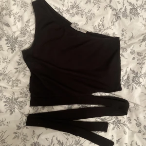 Linne - Ett svart linne med en axel och snören som man knyter runt magen🖤