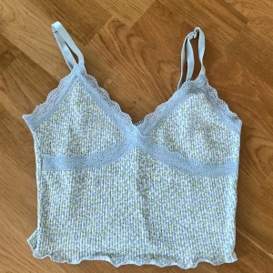Blommig topp - Super gullig blommig top med blå spets ifrån h&m, aldrig använd men justerbara band