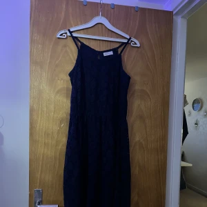 Kort blommönstrad klänning  - En fin kort mörkblå sommarklänning med blommönster i tyget. Blommönstret syns dock inte på bilderna men ja säljer denna klänning då den är för liten för mig. Bra skick 