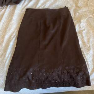 Brun kjol i mocka-material (vet ej om äkta) med en fungerande dragkedja och ett band på baksidan för att justera midjan. Pärlor och broderat i nederkanten, inga pärlor saknas. Sista bilden är bara för stilinspiration 