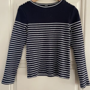 Marinblå vitrandig tröja - Marinblå långärmad tröja med vita ränder och guldiga knappar på axlarna. Långärmad och lite tjockare i materialet. Från bik bok. Använ med i bra skick,