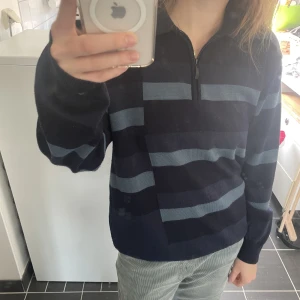 Blårandig tröja - Blå tröja med halv zip-up. Randig och lite asymmetriskt mönster. Storlek L men snygg som oversize. Något nopprig annars inga defekter. 