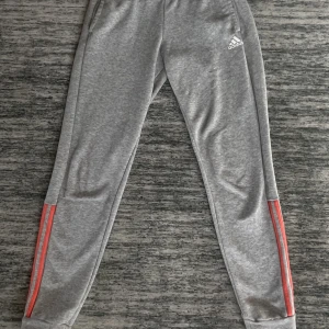 Adidas byxor - Säljer ett par adidas mjukisbyxor med rosa/orange detaljer. Byxorna är rätt så lågmidjade. 
