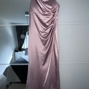 Rosa satin klänning - Rosa lång satinklänning perfekt till bröllop, dop eller andra event. Klänningen är i storlek 44 men passar perfekt för mig som har 36. Klänningen har inbyggd bh. Använd 1 gång. Priset går även att diskuteras.
