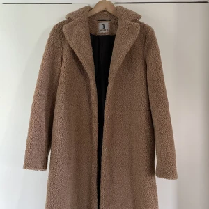 Teddykappa - Beige Teddykappa i fint skick, storlek XS. Går till nedanför knäna på mig 160 cm lång.