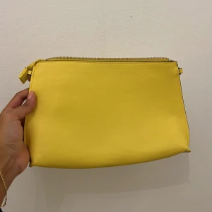 Väska - Gul clutch från H&M. Fin till sommaren. Sparsamt använd. 
