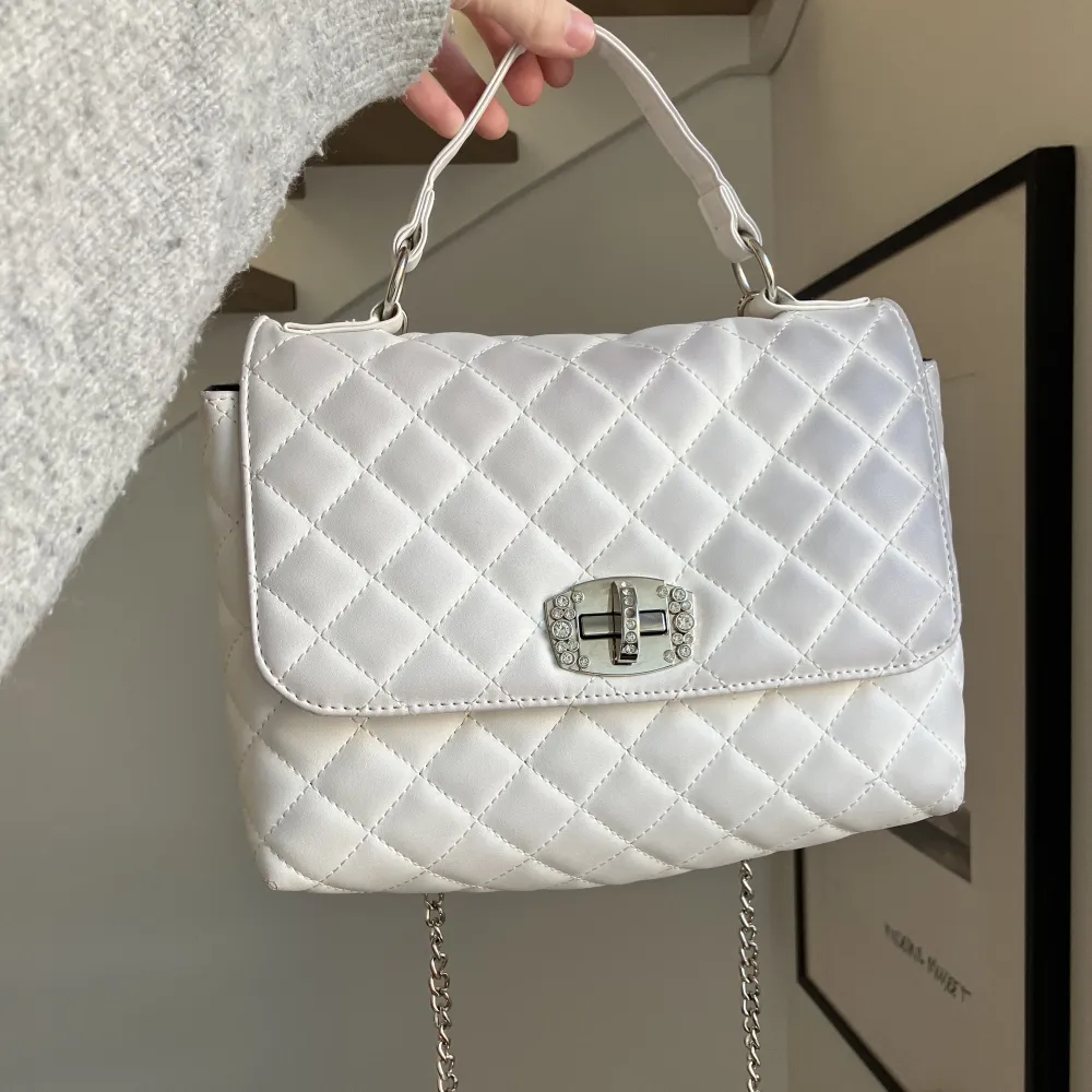 Säljer den här gulliga, vita handväskan med diamantdetaljer. Den har blivit lite missfärgad så den ser lite grå ut. Säljer då jag inte använder längre 💕. Väskor.