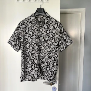 Skjorta paisley  - Kortärmad skjorta med paisleymönster. Tunt och supermjukt tyg som passar till sommaren. Endast använd fåtal gånger. Står att det är storlek XL men skulle säga att det snarare passar M-L. 