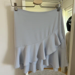 Ljusblå kjol NA-KD - säljer min ljusblåa mini kjol med volanger nedtill från NA-KD, sparsamt använd och inga defekter💘