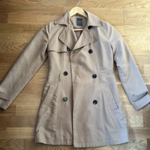 Kort trench coat  - Kort kappa. Använd men i fint skick, knapparna är lite lösa. 