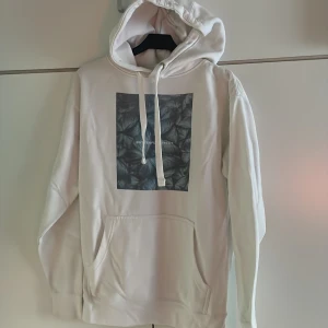 Emplece Hoodie - Säljer en vit huvtröja i bra skick med tryck fram. Trycket föreställer blå fjärilar, ”Butterfly Effect” Pris kan diskuteras 
