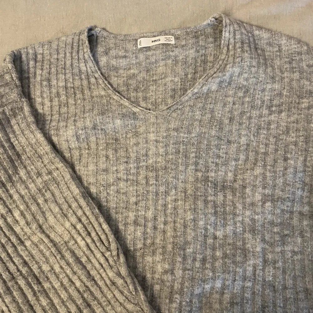 En grå stickad tröja från Mango i strl M. Väldigt sparsamt andvänd så i ett bra skick . Stickat.