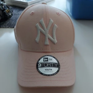 NY keps rosa - Jag säljer min keps då jag inte använder den, den är använd men inte sliten och den är fortfarande i bra skick. Man kan justera den där bak med kardborre