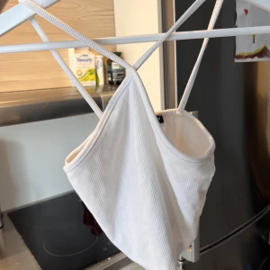 Vit topp med korsad halsringning  - Festlig kort topp från Zara. Använd några gånger men är i gott skick! Liten i storleken. 