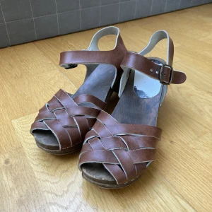 Träskor med klack - Träskor med klack/clogs. Bruna läder band. Syns att de är använda men har inga defekter :)