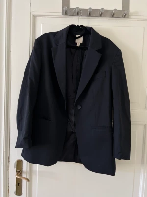 Oversized kavaj  - Overzised kavaj från H&M i ullblandning. Den är väldigt mörk marinblå med mycket svärta i tonen. Kavajen är i superfint skick, använd fåtal gånger. 