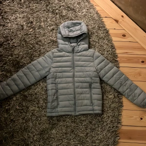 Tunn dunjacka - Säljer denna tunna ljusblåa dunjackan då den inte kommer till användning. Inga hål eller fläckar.