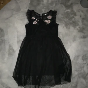 Barnklänning från Lindex  - En svart barnklänning med blommor på. Från Lindex i storleken 134/140🫶🏼