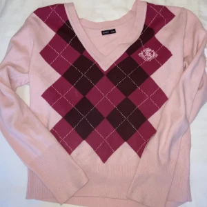 Tröja - Rosa V-ringad tröja med argyle mönster. Det står ingen storlek men den passar bra på mig som vanligtvis har storlek S.